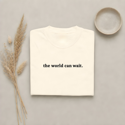 Ivory garment-dyed Comfort Colors tee with "the world can wait" embroidered on the chest, Soft Rebellion