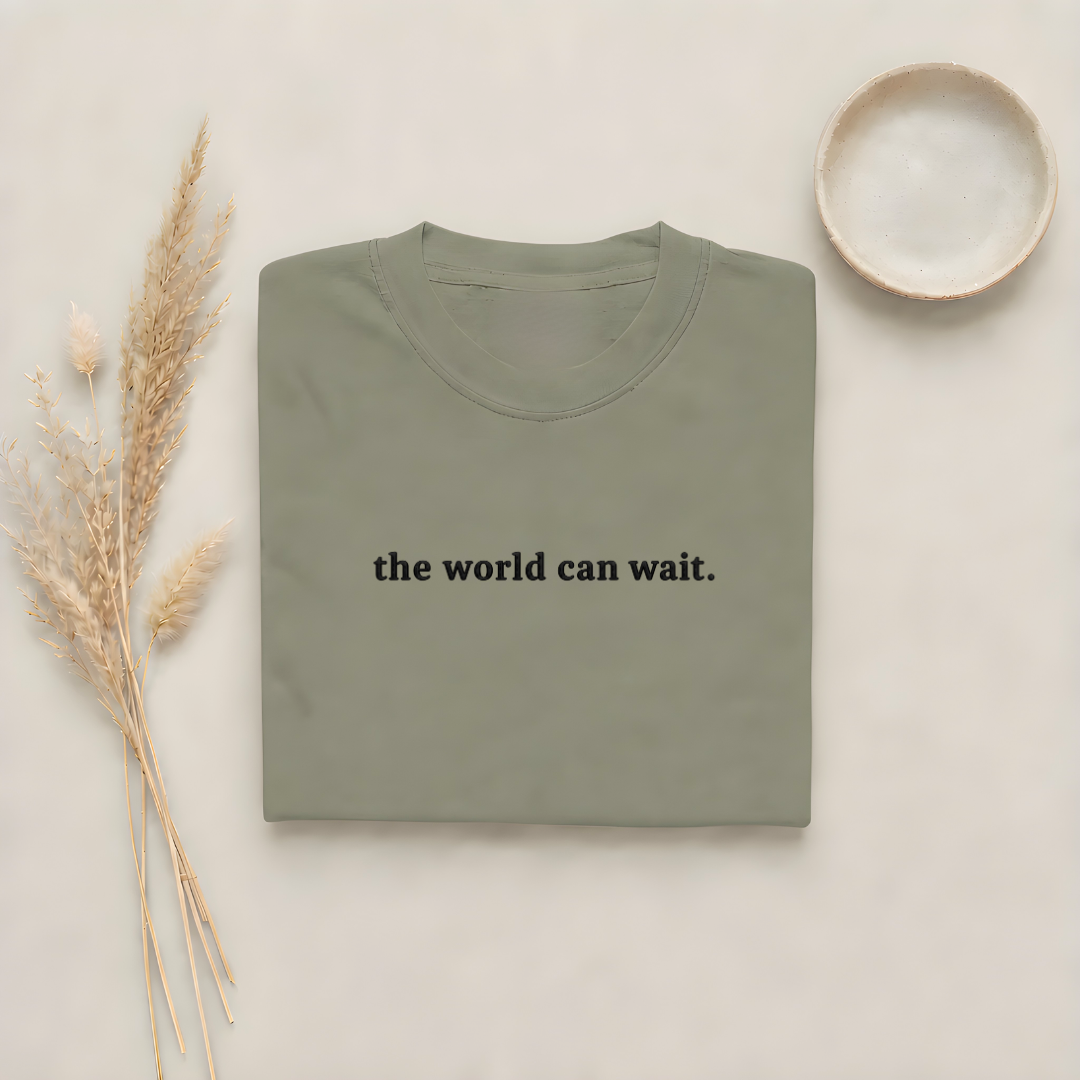 Moss garment-dyed Comfort Colors tee with "the world can wait" embroidered on the chest, Soft Rebellion