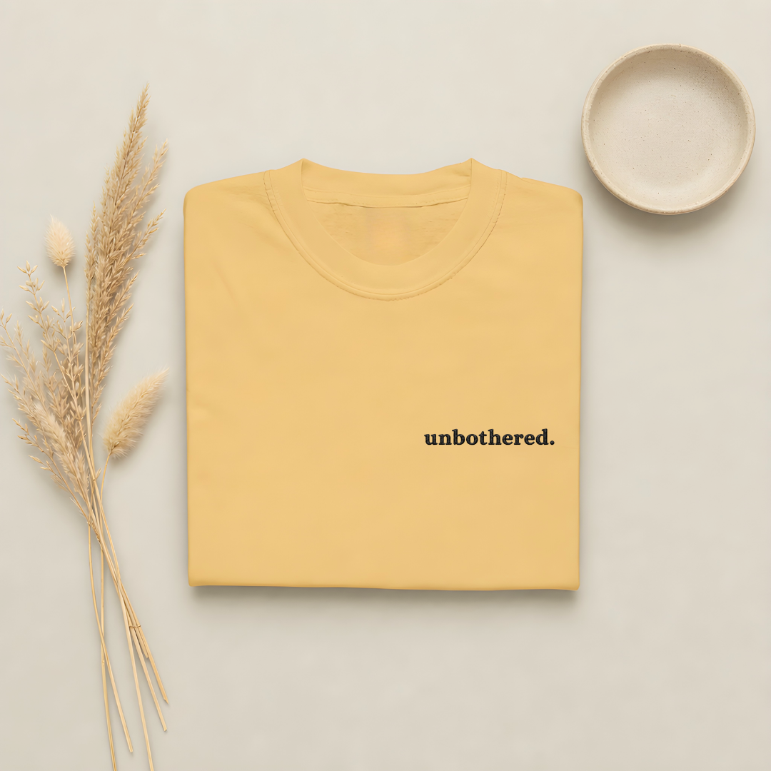 Mustard garment-dyed Comfort Colors tee with "unbothered" embroidered on the chest, Soft Rebellion